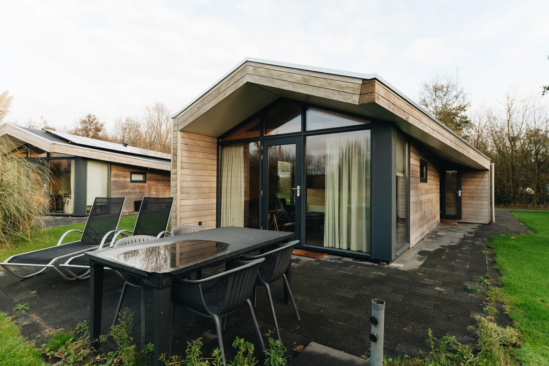 Buitenaanzicht van de moderne houten lodges met privéterras bij Land & Zee.